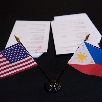 small American and Phillippine flags in the foreground and paperwork in the background.