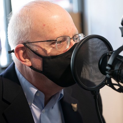 closeup of RIT President Munson talking into a radio station microphone.
