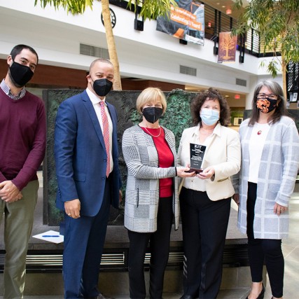 five people standing holding an award.