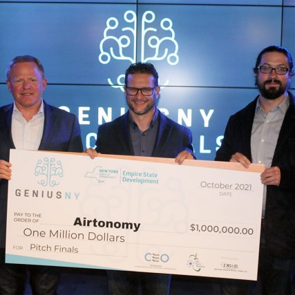 three people holding a giant novelty check for one million dollars.