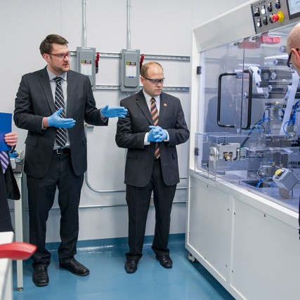 four men looking at battery development processor equipment.