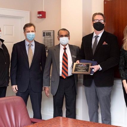 five people standing with one holding a plaque.