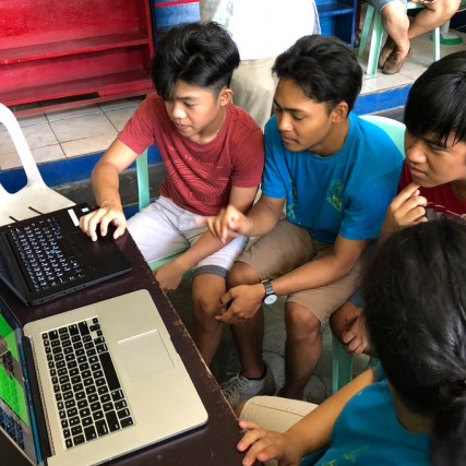 children in the Philippines looking at two laptop computers.
