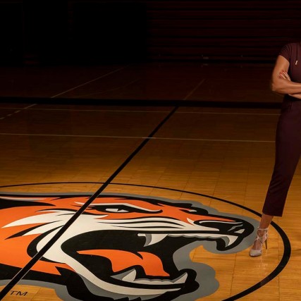 athletic director standing near Tiger logo on basketball court.