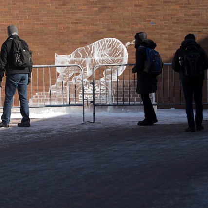 students walking by an ice sculpture of a tiger.