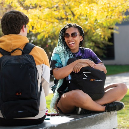 two students sitting outside and laughing.