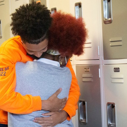 two students hugging in front of school lockers.
