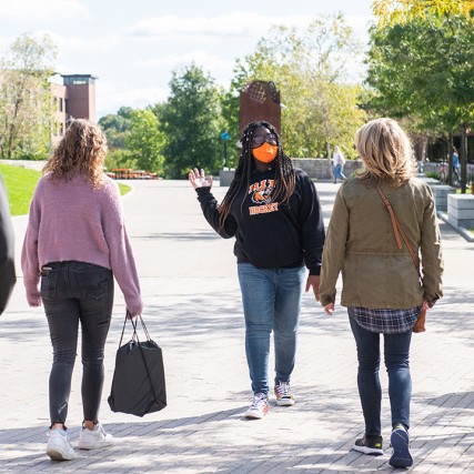 student walking backwards giving a tour of the RIT campus.