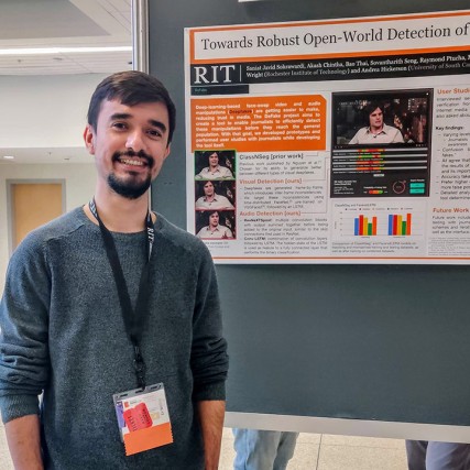 student posing with research poster.