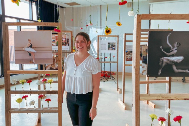 student photographer posing with photos of a ballerina with an artificial leg.