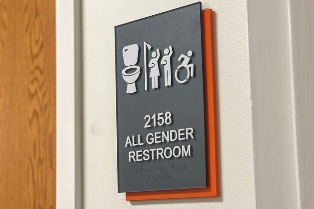 a sign next to a bathroom door indicating all gender restroom with toilet, shower, and wheelchair accessibility.