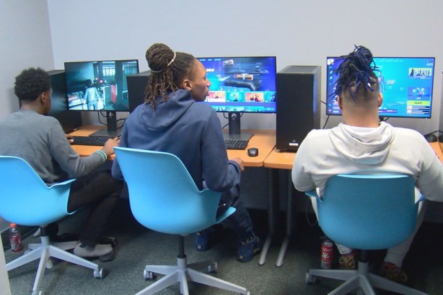 three students sitting at desks with computers.
