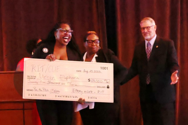 three people standing on a stage holding a giant novelty check.