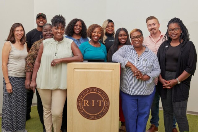 11 people posing for a photo around a podium.