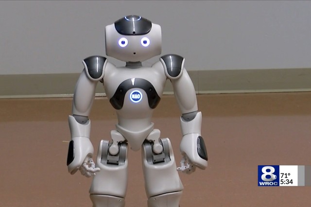 A picture of a small robot with glowing eyes and a logo on the chest that says, "NAO"