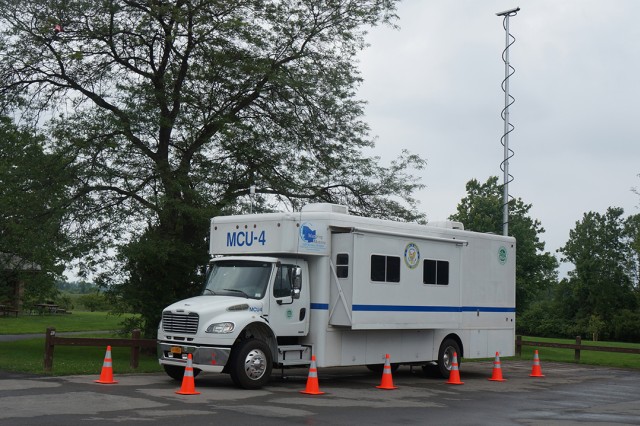 a camper-looking truck with a large antenna attached to the back.