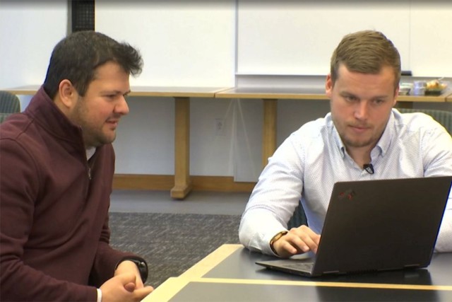 two men looking at a laptop computer.