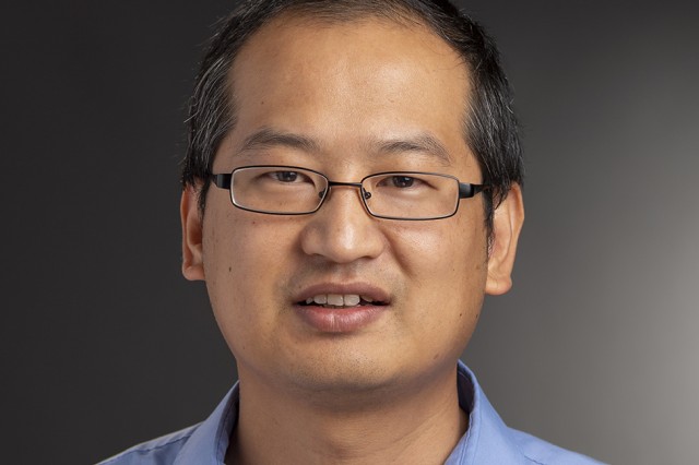 RIT professor, Yunbo Zhang wearing a light blue collared shirt and glasses.