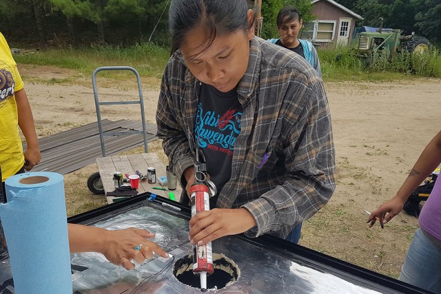 Person works on a solar panel furnace outdoors.