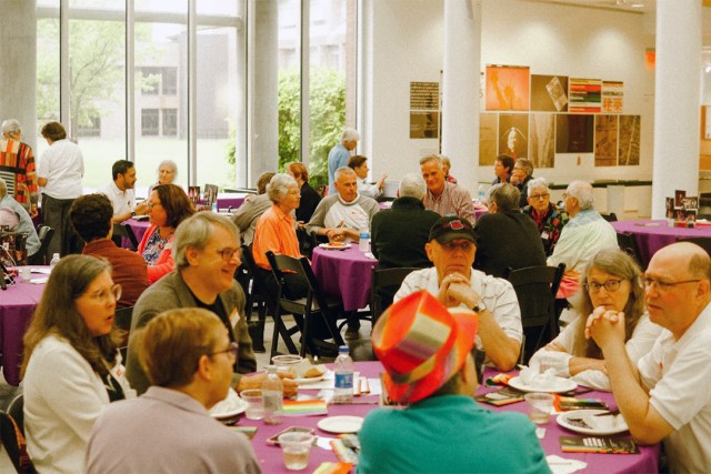crowd of people seated at round banquet tables.