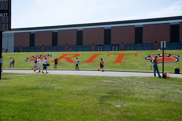 the R I T logo and paw prints spray painted onto a large section of lawn.