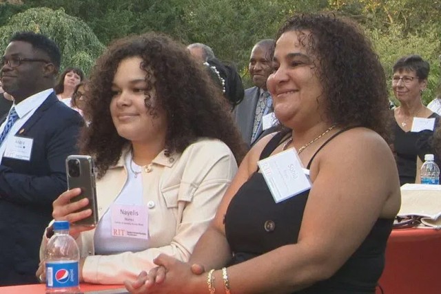 two women standing at a high top table outside.