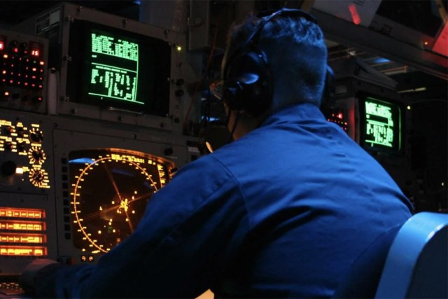 a naval officer is shown in a submarine looking at radars and other information displayed on screens