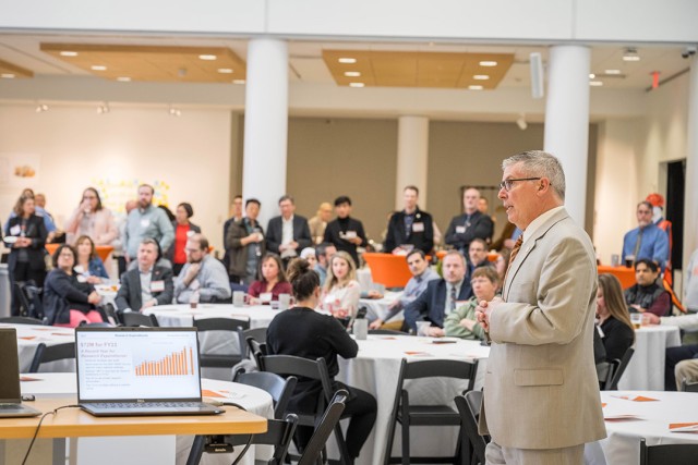 Vice President for Research Ryne Raffaelle is shown on the right side speaking in front of a group of PI Millionaires.