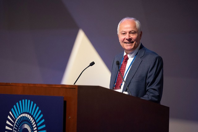 Nabil Nasr is pictured standing at a podium giving a speech.