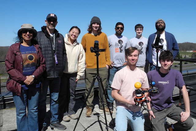 a group of researchers gathers around a camera used to capture the eclipse.