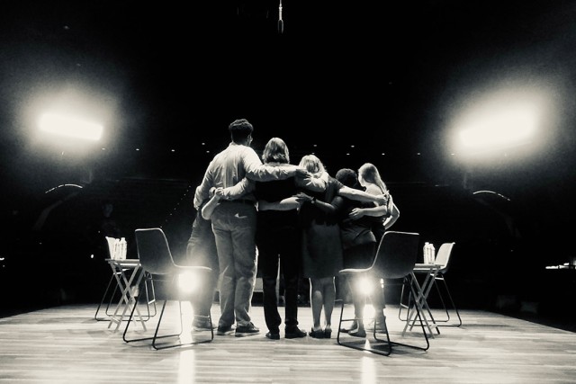 a black and white photo of the cast shown facing the audience.