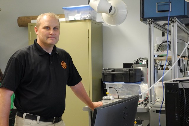 a man is shown standing next to equipment in a research lab.
