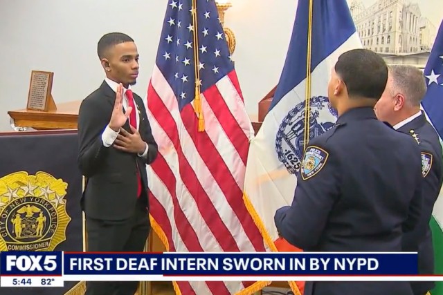 Heriberto Almone appears on the left getting sworn in by offers standing on the right with an american flag in the background.