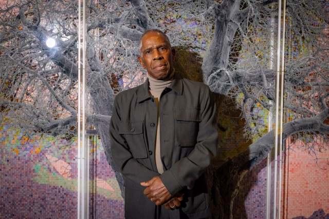 Man standing in front of a tree-themed art installation.