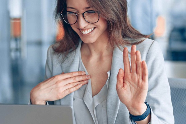 A woman uses sign language while looking at her computer in an office. 