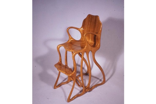 a hand carved wooden high chair on a purple background.
