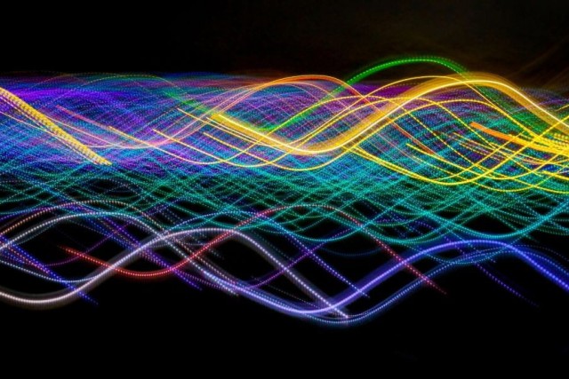 Photonic rays stretch like ribbons in multicolor across a black background