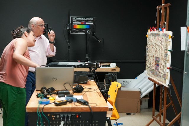 2 individuals using imaging equipment to inspect a piece of artwork