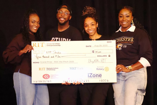 four students hold a 15 thousand dollar check on a stage