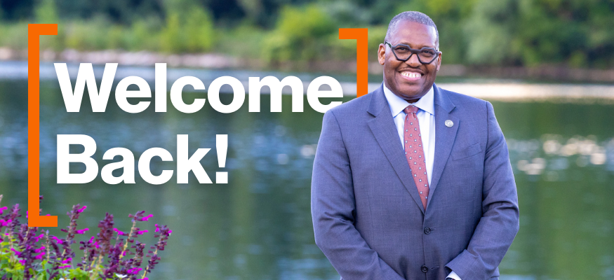 Man standing in front of lake. Text read Welcome Back