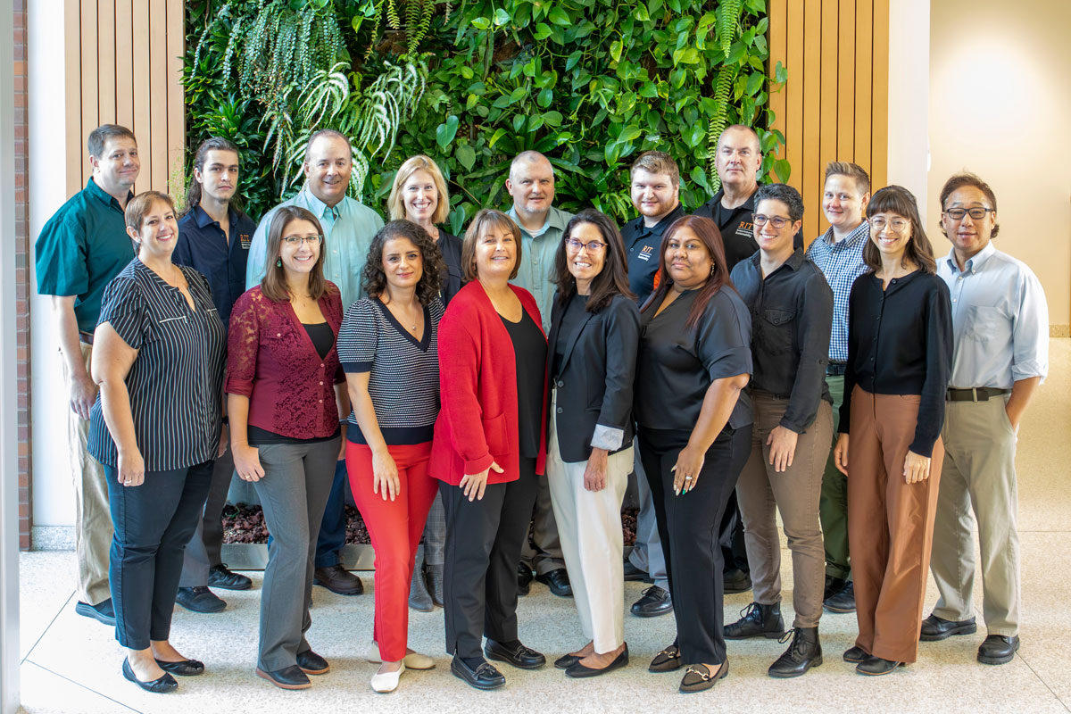 group photo of staff in front of GIS green plant wall