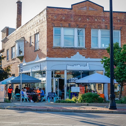 outside view of The Tool Library building with a couple tents outside where people are doing repairs