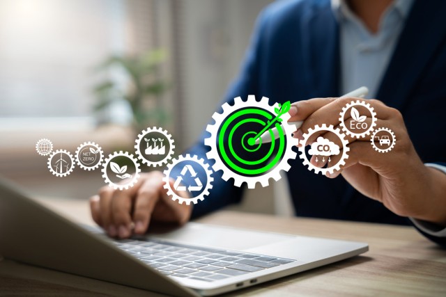 icons of gears appear overlayed on top of an image of a person typing on a laptop