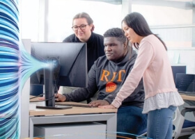 Three students looking at a computer monitor.