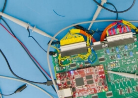 A circuit board with various wires connected to it, sitting on top of a blue silicone pad.