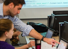 An instructor pointing to the screen, helping a student.