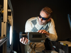 Two people calibrating an imaging device against a black backdrop.