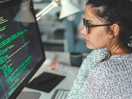 A student looks at a computer screen with code on it.