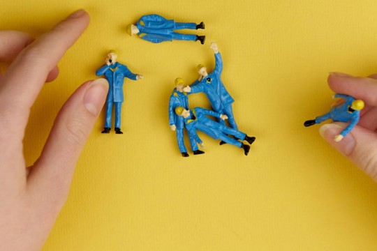 Hands playing with little figurines.