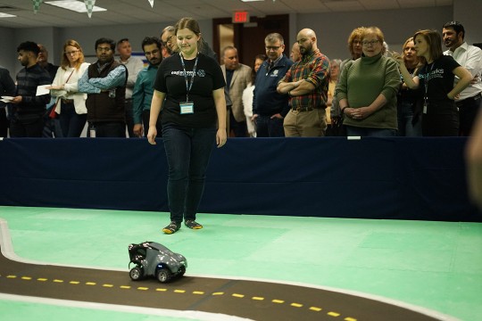 student watching small car driving on paper road.